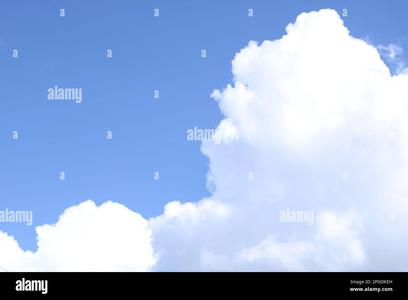 Large white fluffy cloud in a bright blue sky on a summers day Stock Photo