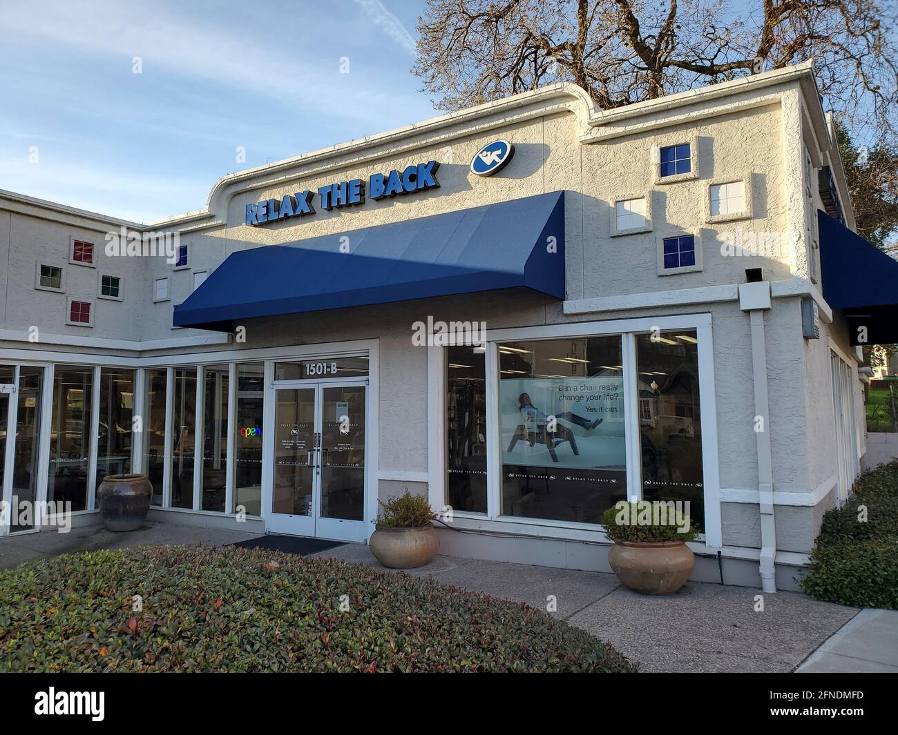 Angled view of a Relax the Back store, with a rainbowneon 'open' sign