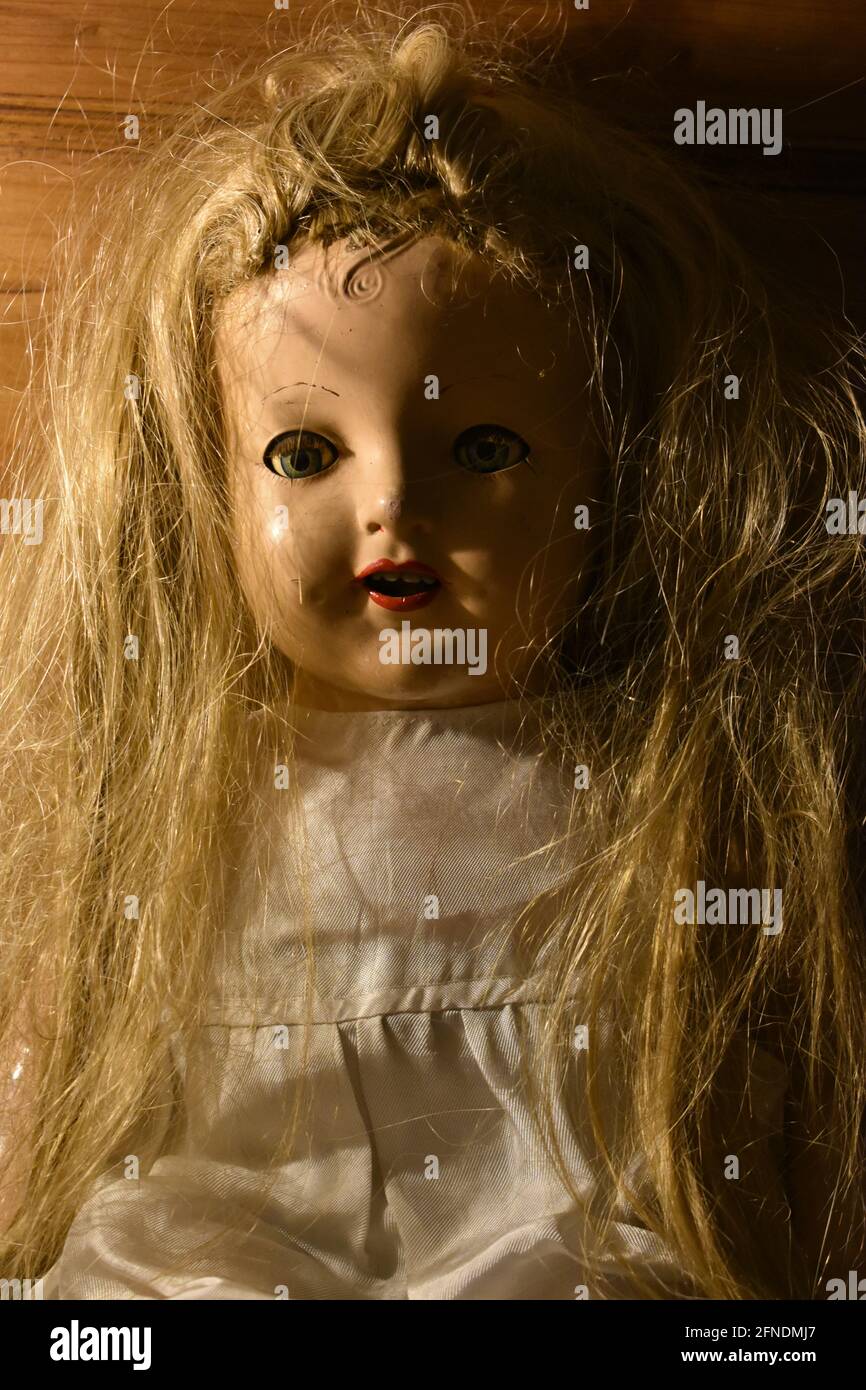 Closeup of a creepy old doll face with disheveled hair Stock Photo