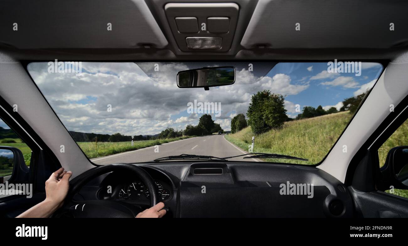 Motorist driver driving steering car outlook on dashboard and contraflow traffic with daytime running light on tranquil country road Stock Photo