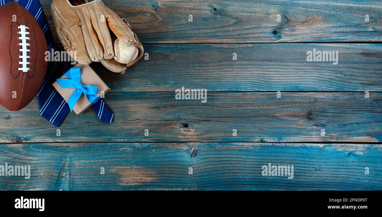 Football, baseball, mitt, neck tie and gift box on faded blue wood for happy fathers day concept background Stock Photo