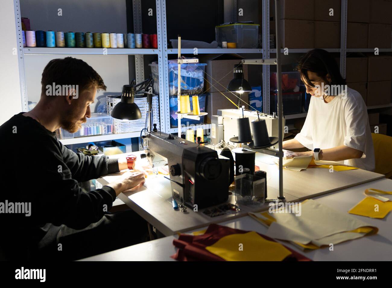 Two tailors sew on sewing machines in atelier. Team of clothes designers entrepreneurs work together Stock Photo