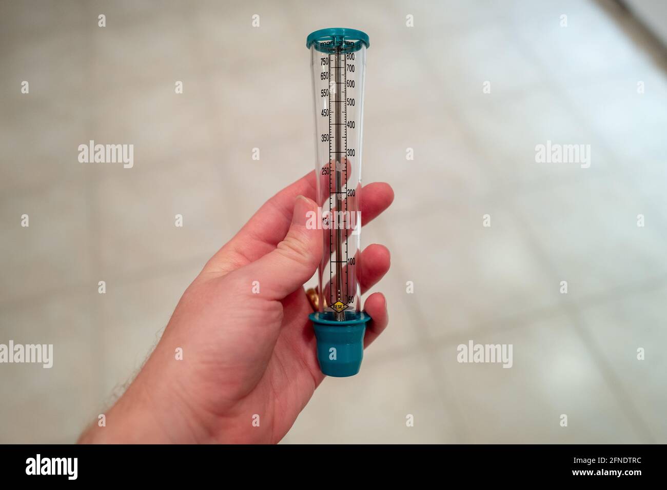 Closeup of a person holding the Monaghan TruZone Peak Flow Meter, in