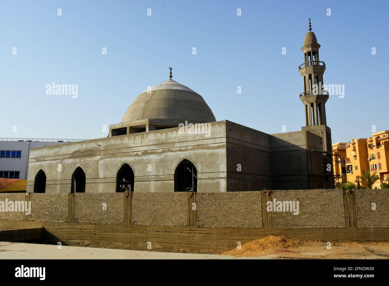 A new mosque under construction against the sunny blue sky, building a new mosque with its big dome in cement Stock Photo