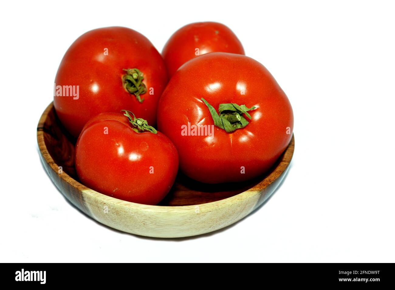 red fresh tomatoes in a brown wooden bowl isolated on a white background Stock Photo