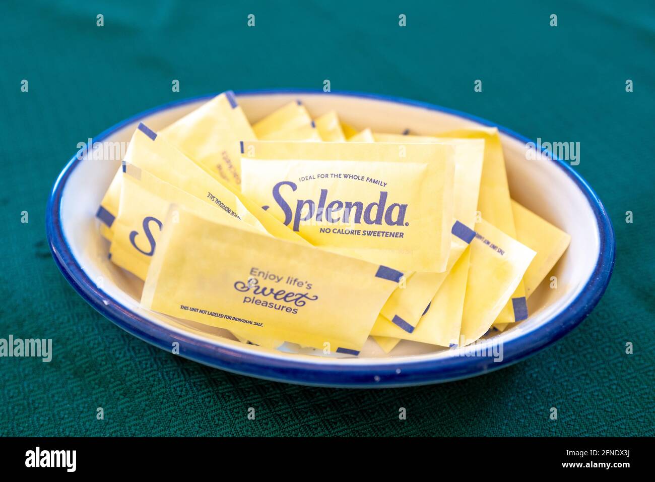 Close-up of single-serve Splenda brand sugar substitute packets, resting in a blue and white plate on a green tablecloth, February 17, 2021. () Stock Photo