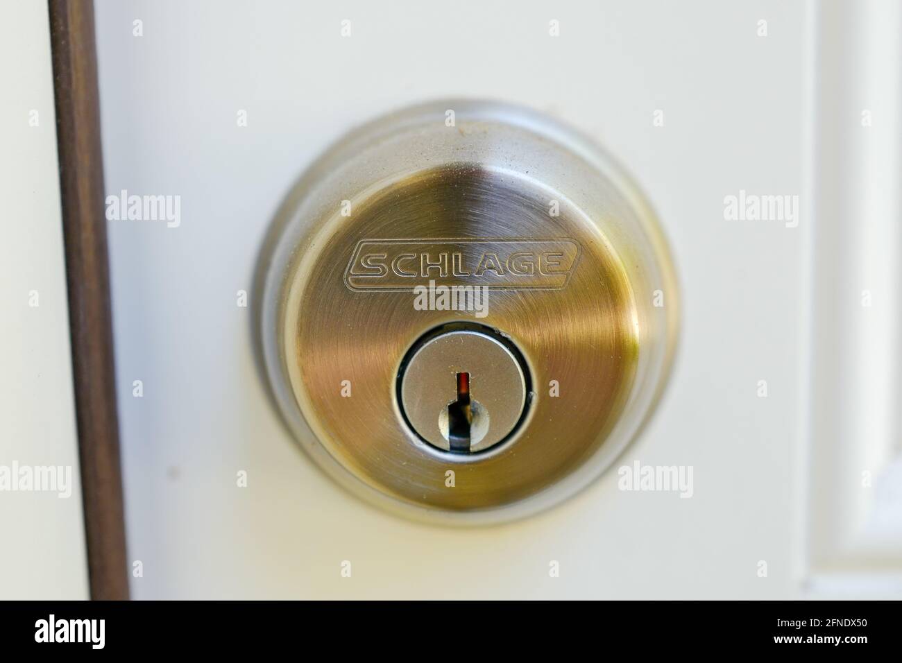 Close-up of a bronze deadbolt with a Schlage logo, attached to a white door, February 17, 2021. () Stock Photo