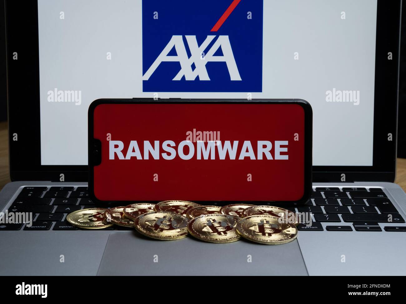 AXA logo on the blurred background and word RANSOMWARE on the smartphone in front. Stafford, United Kingdom, May 16, 2021. Stock Photo