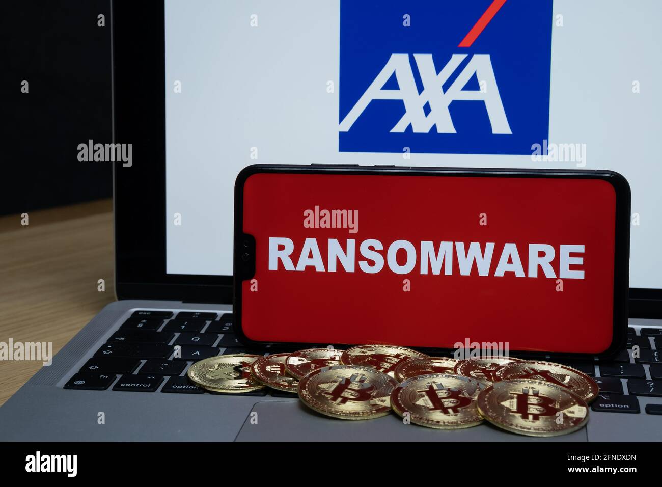 AXA logo on the blurred background and word RANSOMWARE on the smartphone in front. Stafford, United Kingdom, May 16, 2021. Stock Photo