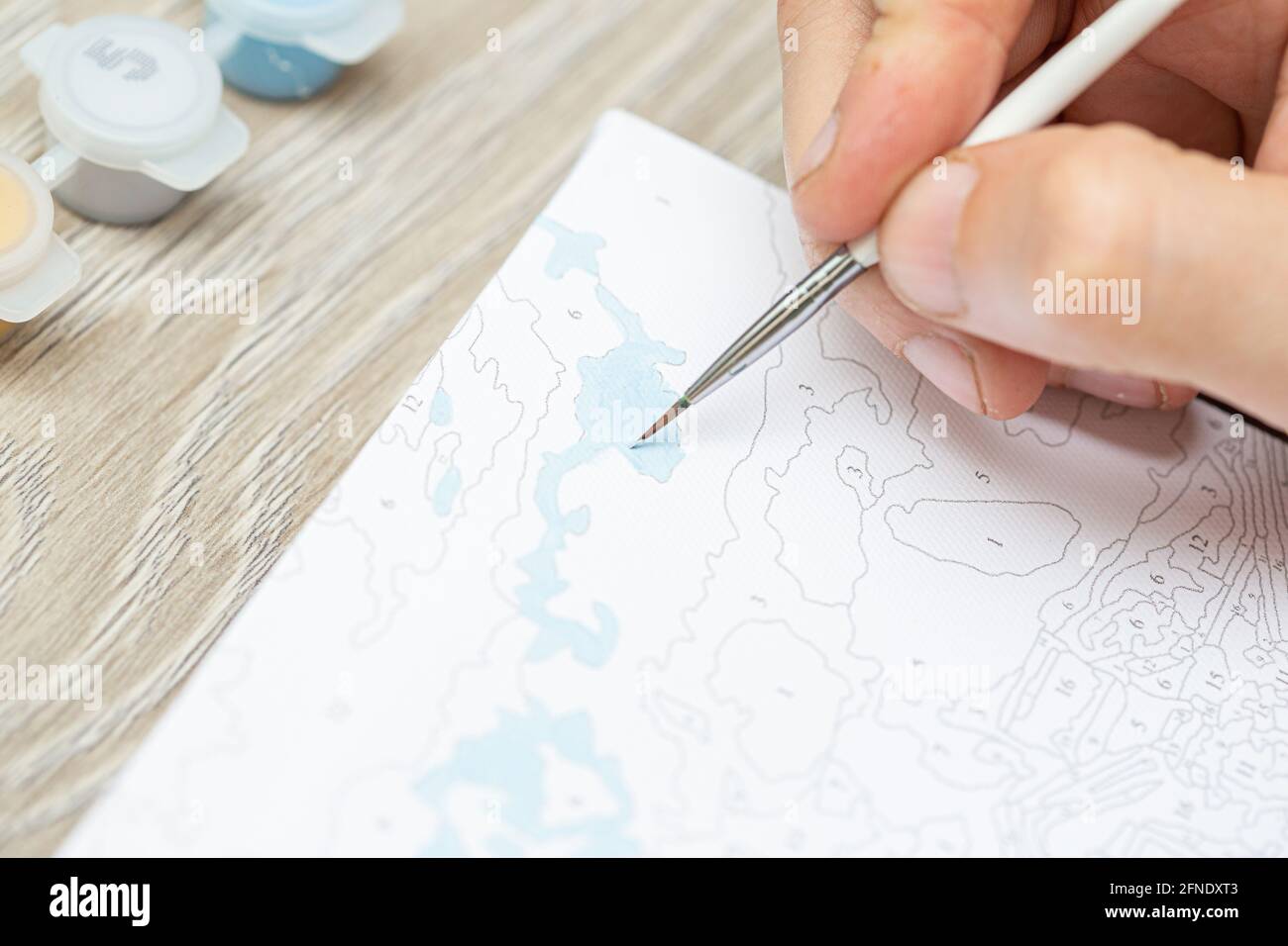 A Mans Hand Holds A Brush And Draws A Picture By Numbers Drawing On Canvas Numbered Paint Cans Creative Hobby Painting For Beginners Closeup Sele Stock Photo Alamy