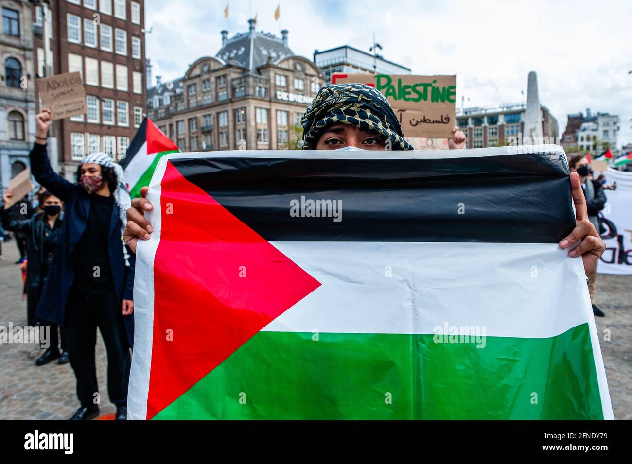 Amsterdam, Netherlands. 16th May, 2021. A protester seen holding a Palestinian flag during the demonstration.The Netherlands and thousands of Dutch people gathered at the Dam Square in Amsterdam to condemn the Israeli attacks and the forced evictions of Palestinians from Sheikh Jarrah neighborhood in occupied East Jerusalem. Credit: SOPA Images Limited/Alamy Live News Stock Photo