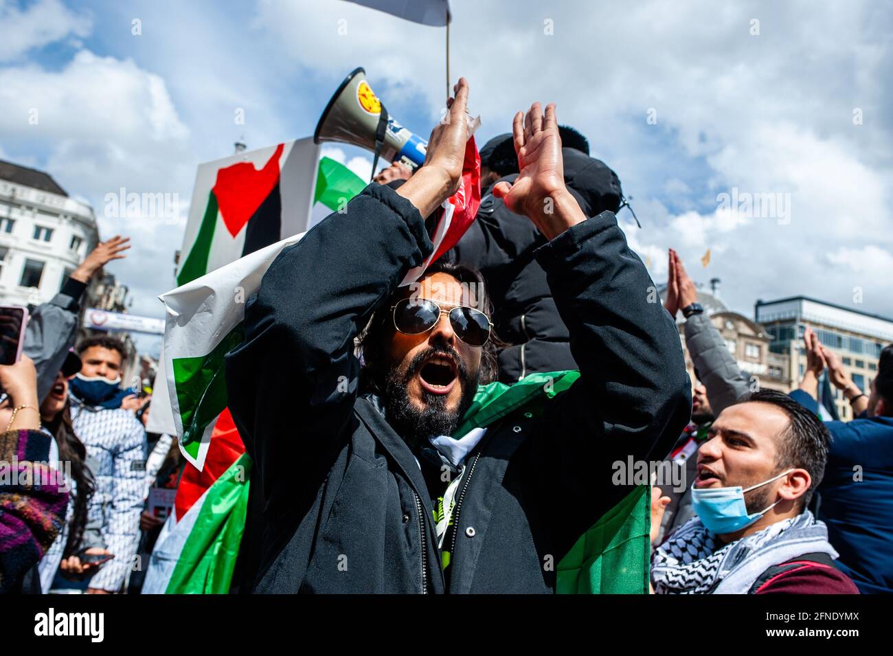 Amsterdam, Netherlands. 16th May, 2021. A protester seen shouting slogans while clapping during the demonstration.The Netherlands and thousands of Dutch people gathered at the Dam Square in Amsterdam to condemn the Israeli attacks and the forced evictions of Palestinians from Sheikh Jarrah neighborhood in occupied East Jerusalem. (Photo by Ana Fernandez/SOPA Images/Sipa USA) Credit: Sipa USA/Alamy Live News Stock Photo