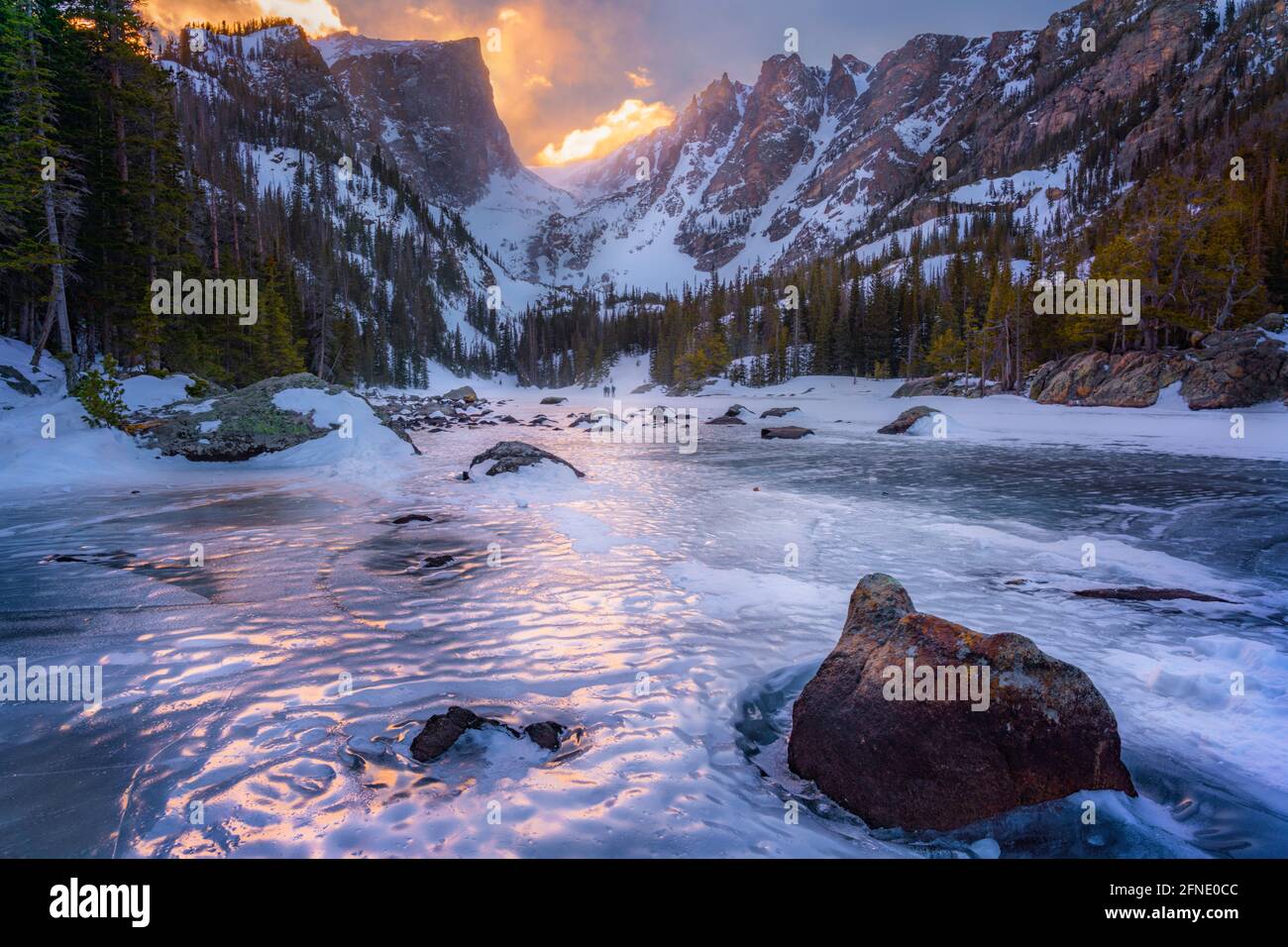 warm sunlight across mountain peaks and frozen lake Stock Photo