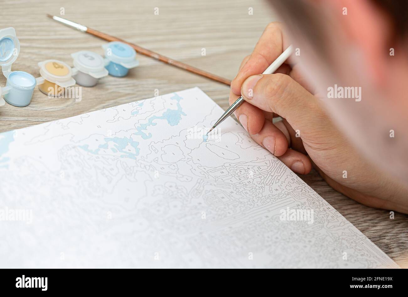 A Mans Hand Holds A Brush And Draws A Picture By Numbers Drawing On Canvas Numbered Paint Cans Creative Hobby Painting For Beginners Closeup Sele Stock Photo Alamy