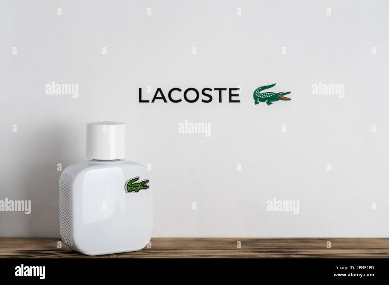 Minsk, Belarus 07.05.2021: white perfume bottle with Lacoste logo, on wooden surface on white background Stock Photo