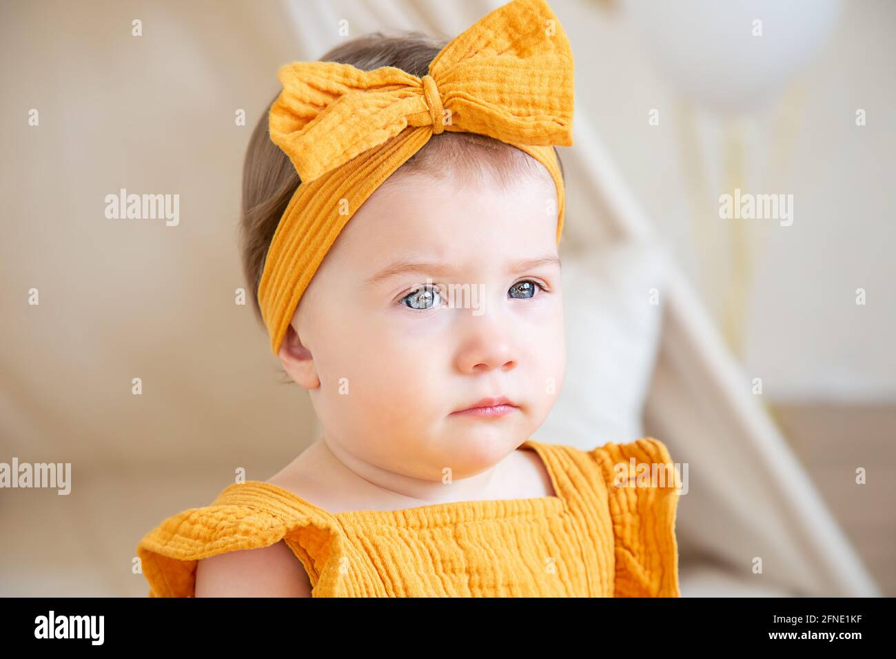 A pretty oneyearold caucasian girl in yellow clothes sits on the