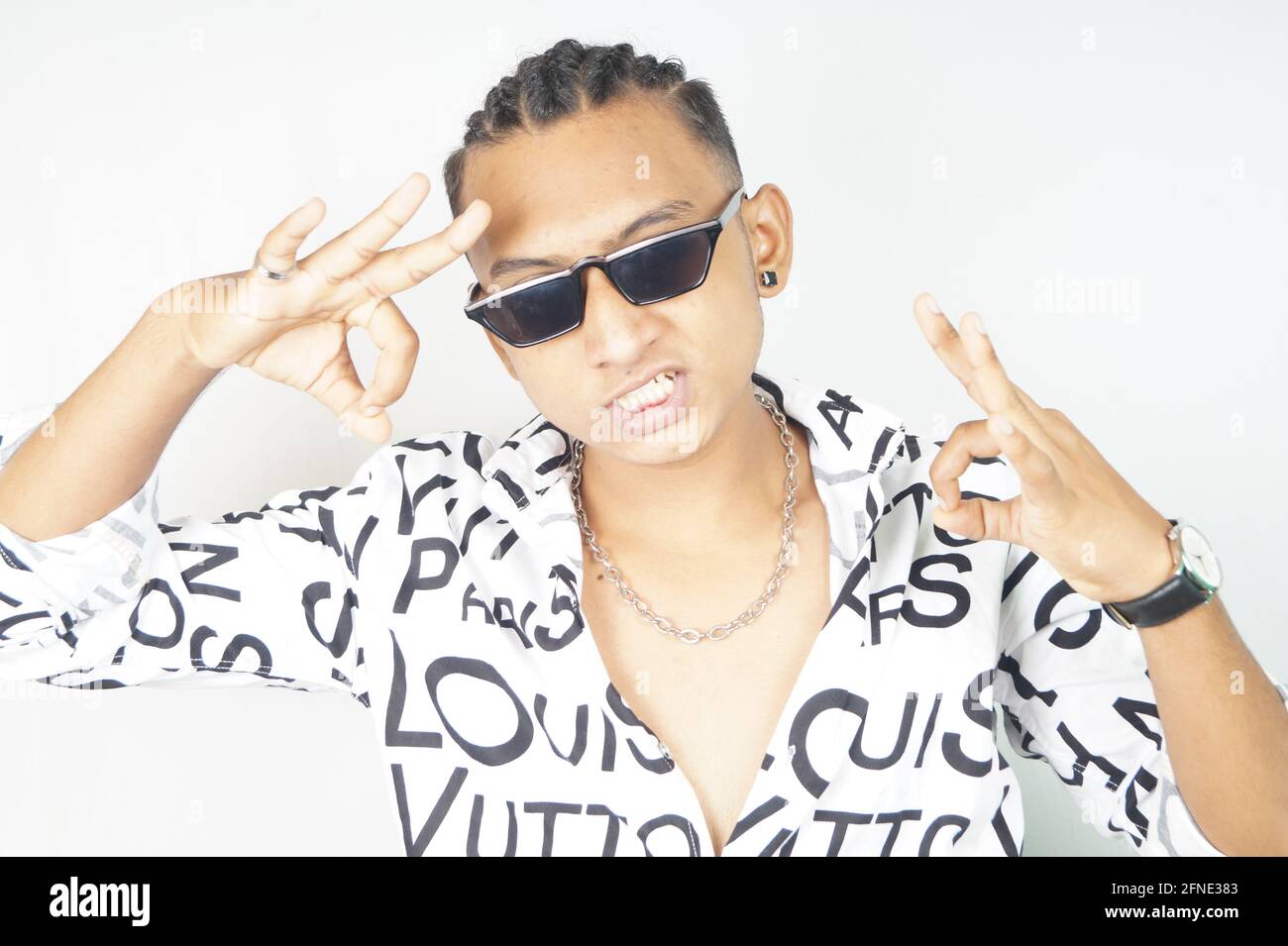 Portrait of an Indian male in a fashionable shirt and sunglasses showing Perfect gesture Stock Photo