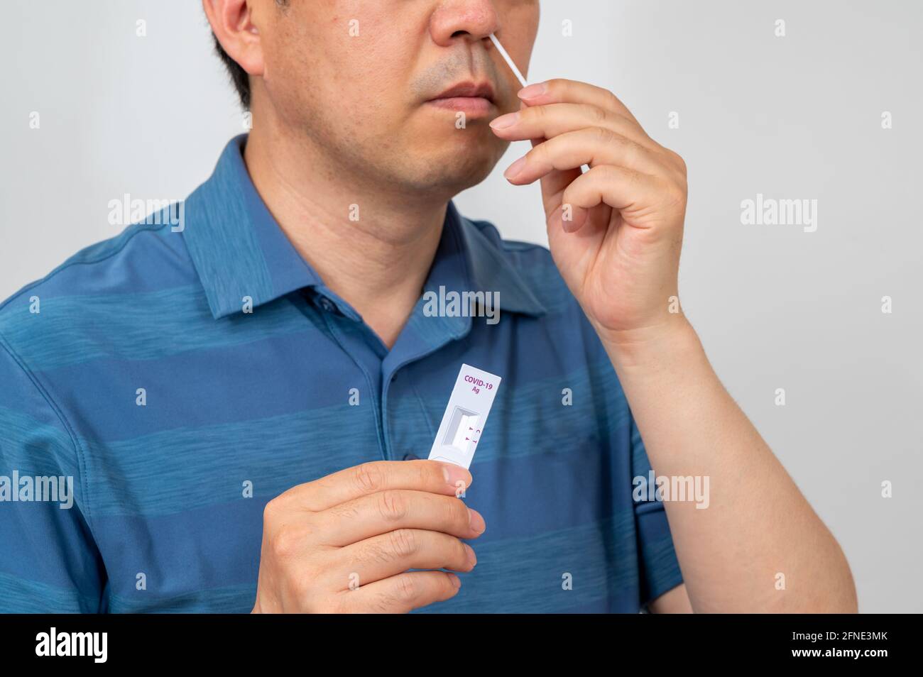 Middle-aged Asian man tested for coronavirus using COVID-19 home antigen kits. Stock Photo