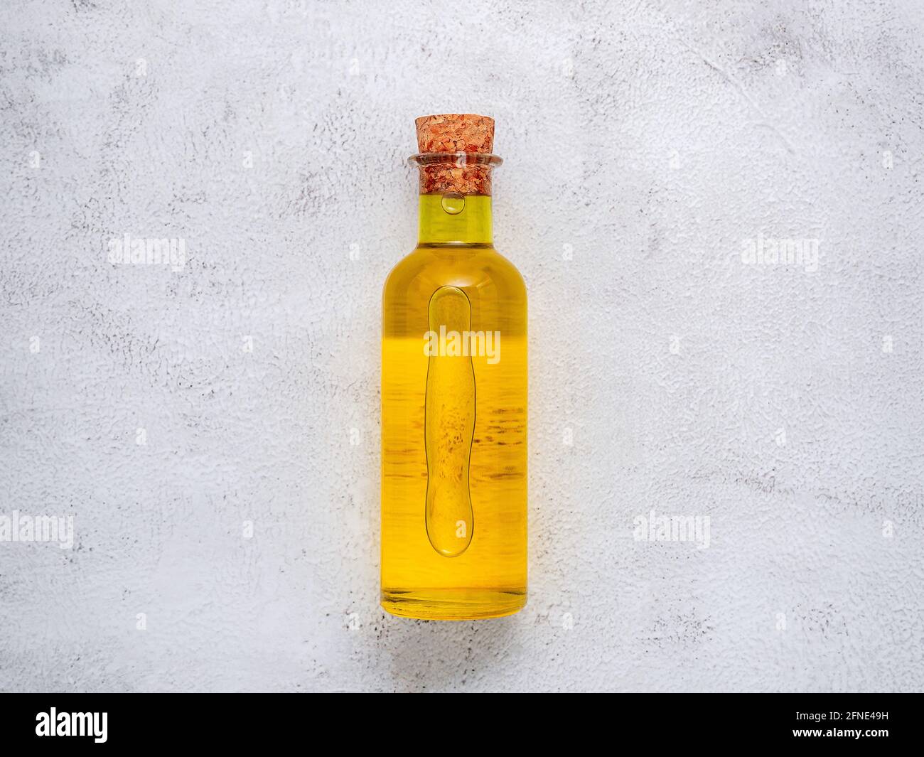 Glass bottle of olive oil and olive branch set up on white concrete ...