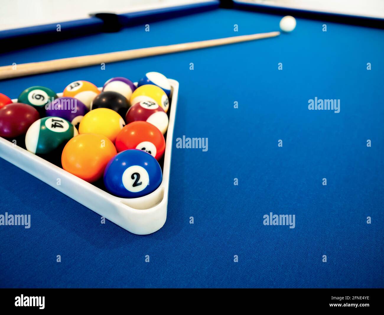 Billiard balls in the white triangle and cue on the blue table with