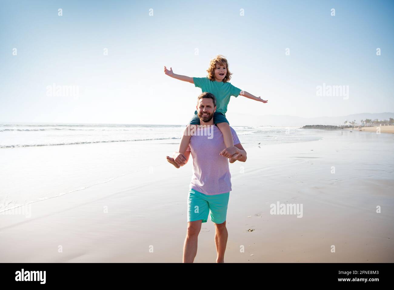 Little boy kid with daddy carrying him on shoulders. Dad and child walk together. Family travel, vacation, father's day concept. Stock Photo