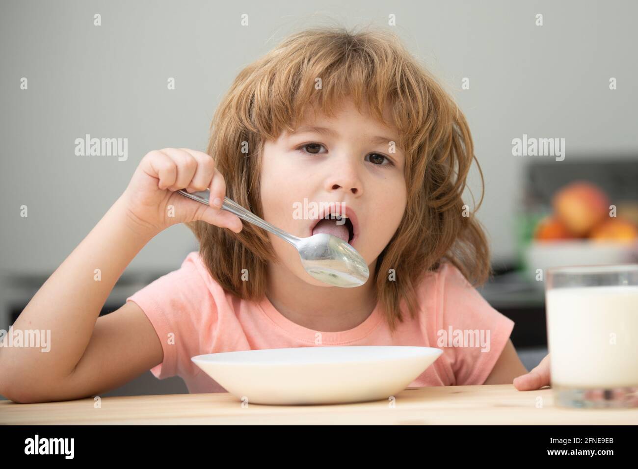 Caucasian toddler child boy eating healthy soup in the kitchen. Child nutrition. Stock Photo