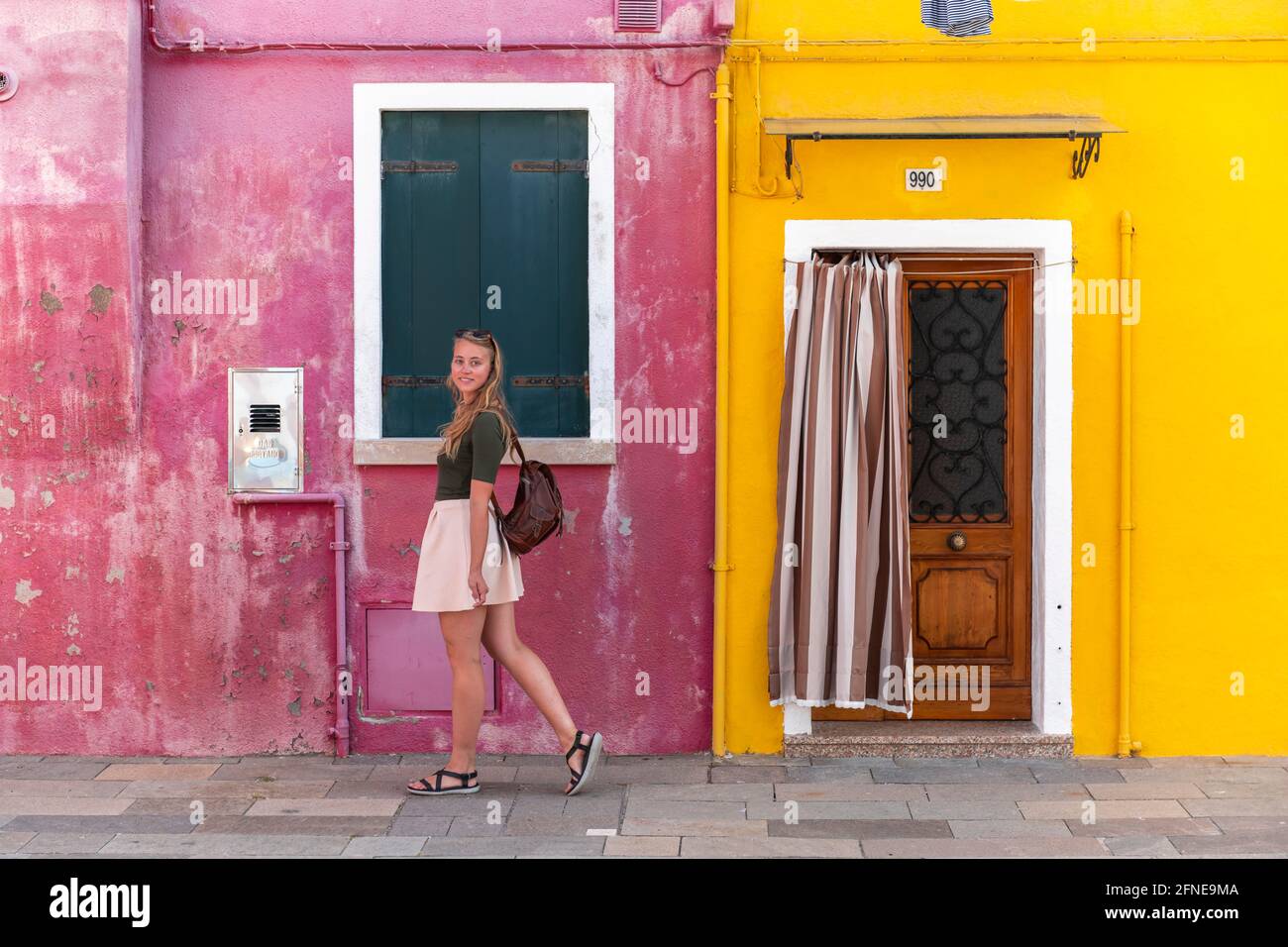 Young woman in front of colorful house, colorful house facades, tourist on Burano island, Venice, Veneto, Italy Stock Photo