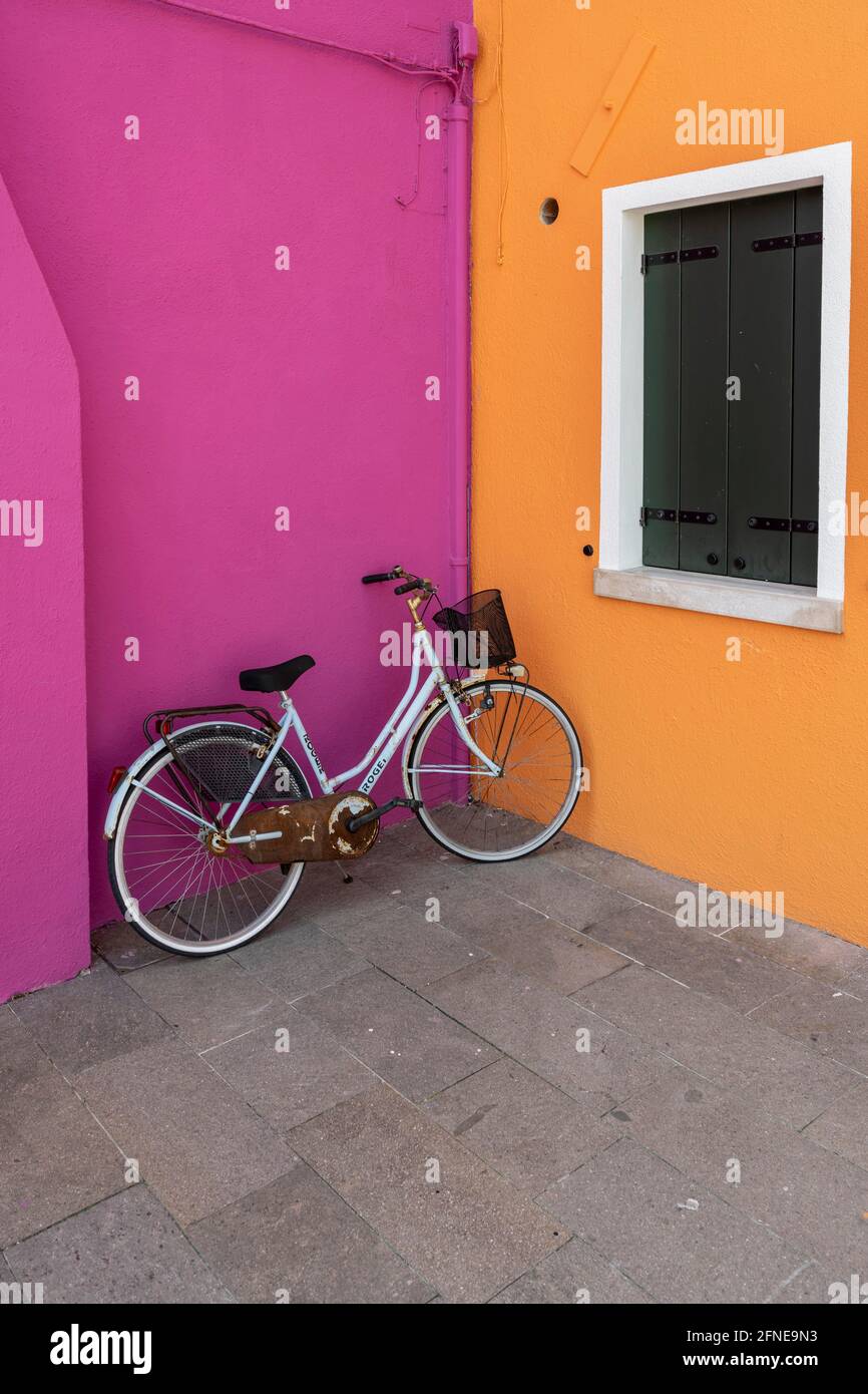 Bicycle leaning against house wall, orange and pink house wall, colorful house wall, colorful facade, Burano Island, Venice, Veneto, Italy Stock Photo
