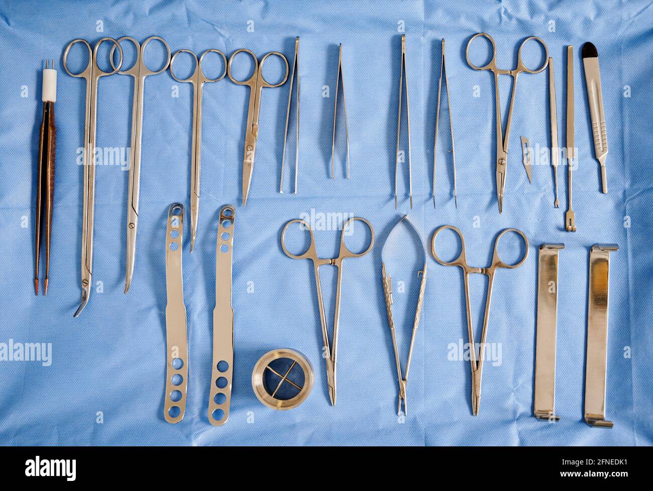 Set of various stainless steel tools for plastic surgery: curved scissors, forceps, scalpel and tweezers in operating room. Concept of aesthetic surgery, medical instruments and preparation. Top view Stock Photo