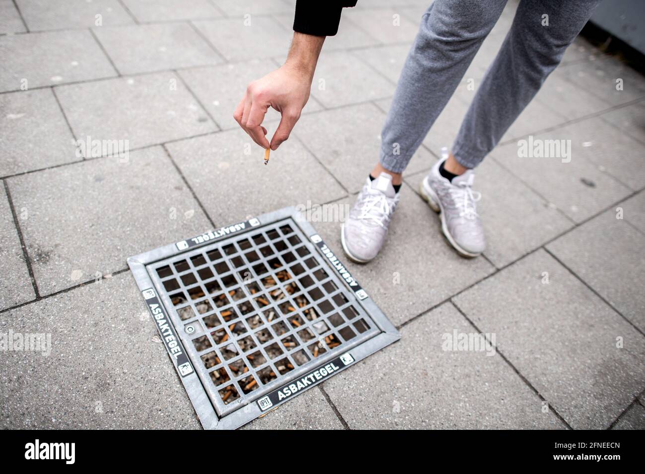 Oldenburg, Germany. 22nd Mar, 2021. A young man throws a cigarette butt