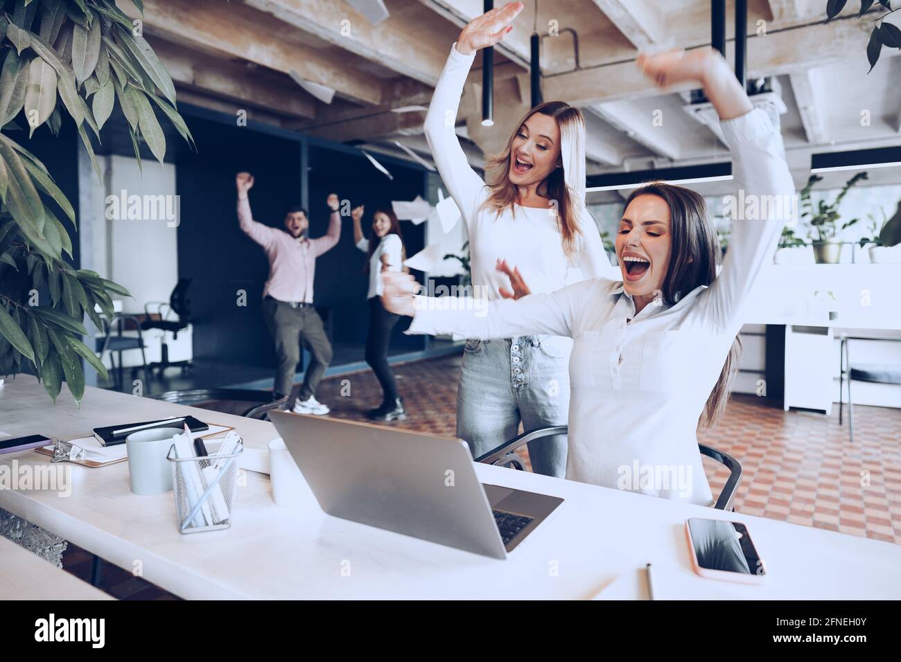 Two young happy businesswomen celebrating project success in office ...