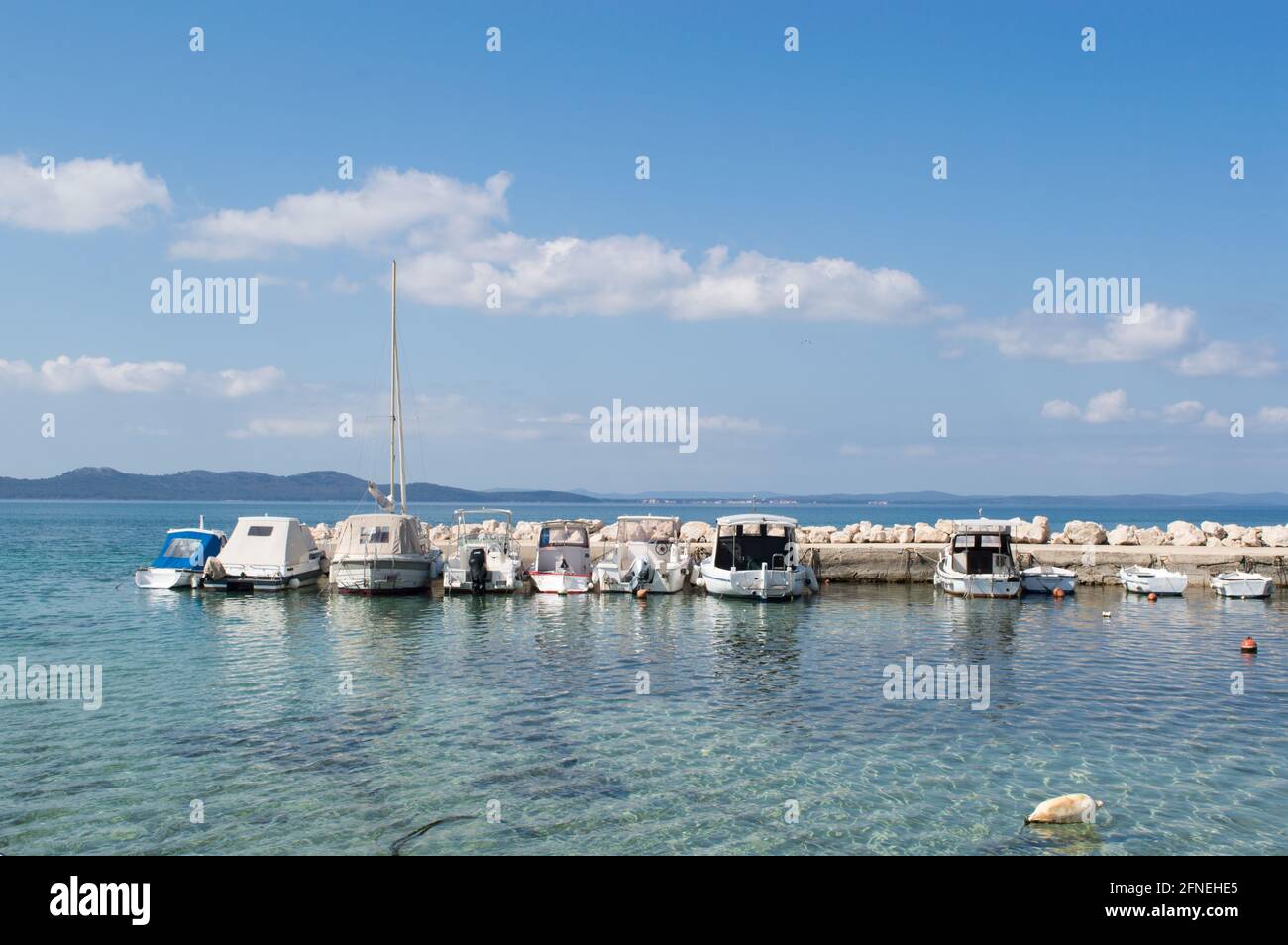 Small recreational boats moored on the stone pier, blue and clean Adriatic sea, in Zadar, Croatia Stock Photo