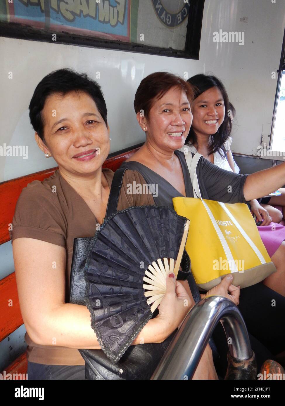 Three Filipino women smiling at the back of an aircon bus in Novaliches, Manila, Philippines Stock Photo