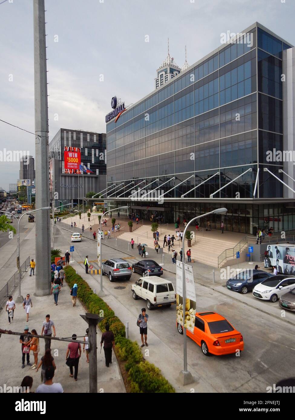 Cars, motorcycles and other traffic driving by an indoors shopping mall on the avenues of Novaliches, Manila, Philippines Stock Photo