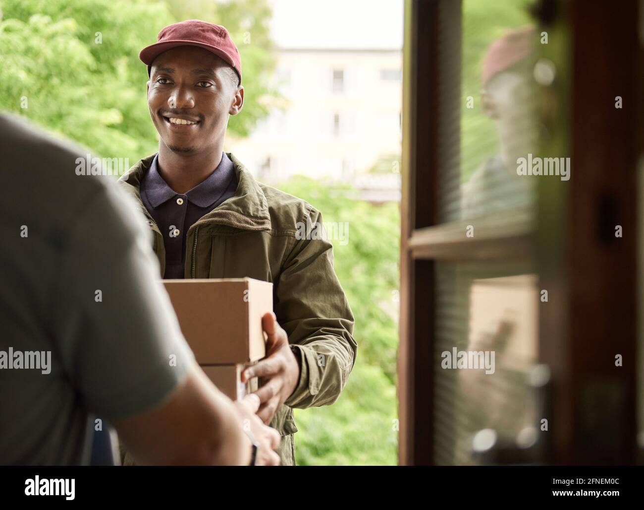 Smiling African courier delivering packages to a customer Stock Photo