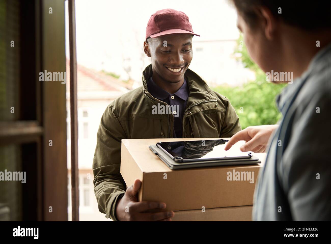 Smiling African courier getting a customer's digital signature for a delivery Stock Photo