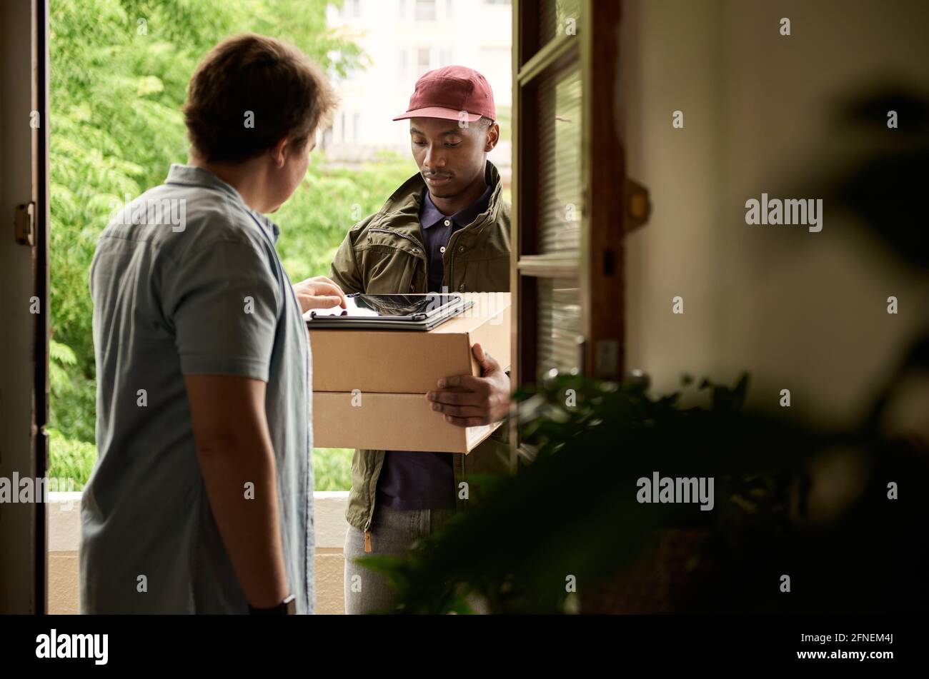 Man digitally signing a tablet for a courier delivery Stock Photo