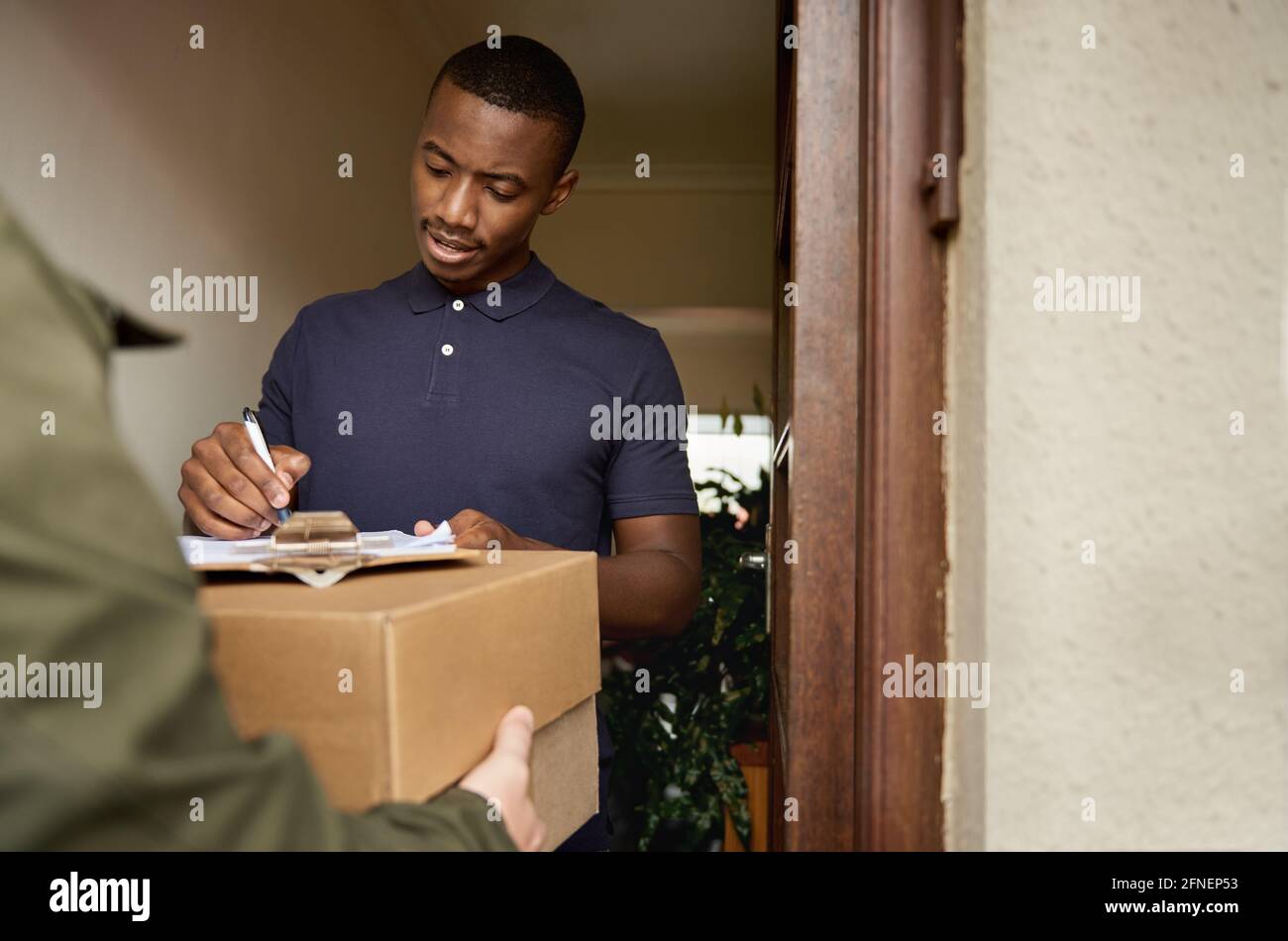 Young African man signing a clipboard for a delivery Stock Photo