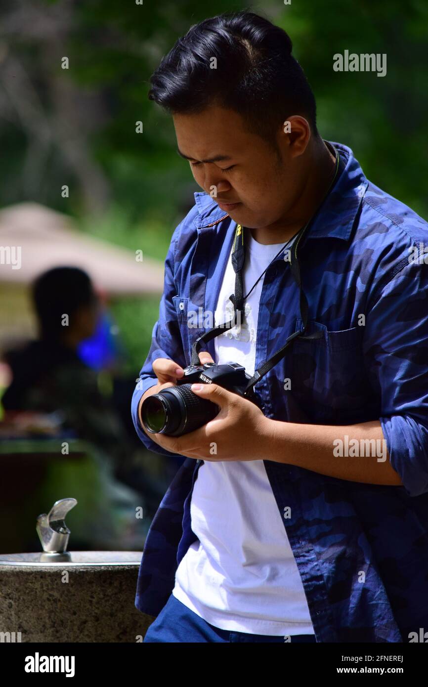 Asian Filipino man taking pictures with a DSLR during Philippines Independence day 2015, Vincent Massey Park, Ottawa, Ontario, Canada Stock Photo
