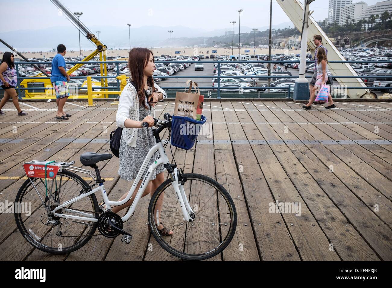 Young Asian Japanese woman walking her bike on the waterfront in Pacific Park, Santa Monica, Los Angeles, California, USA, United States Stock Photo
