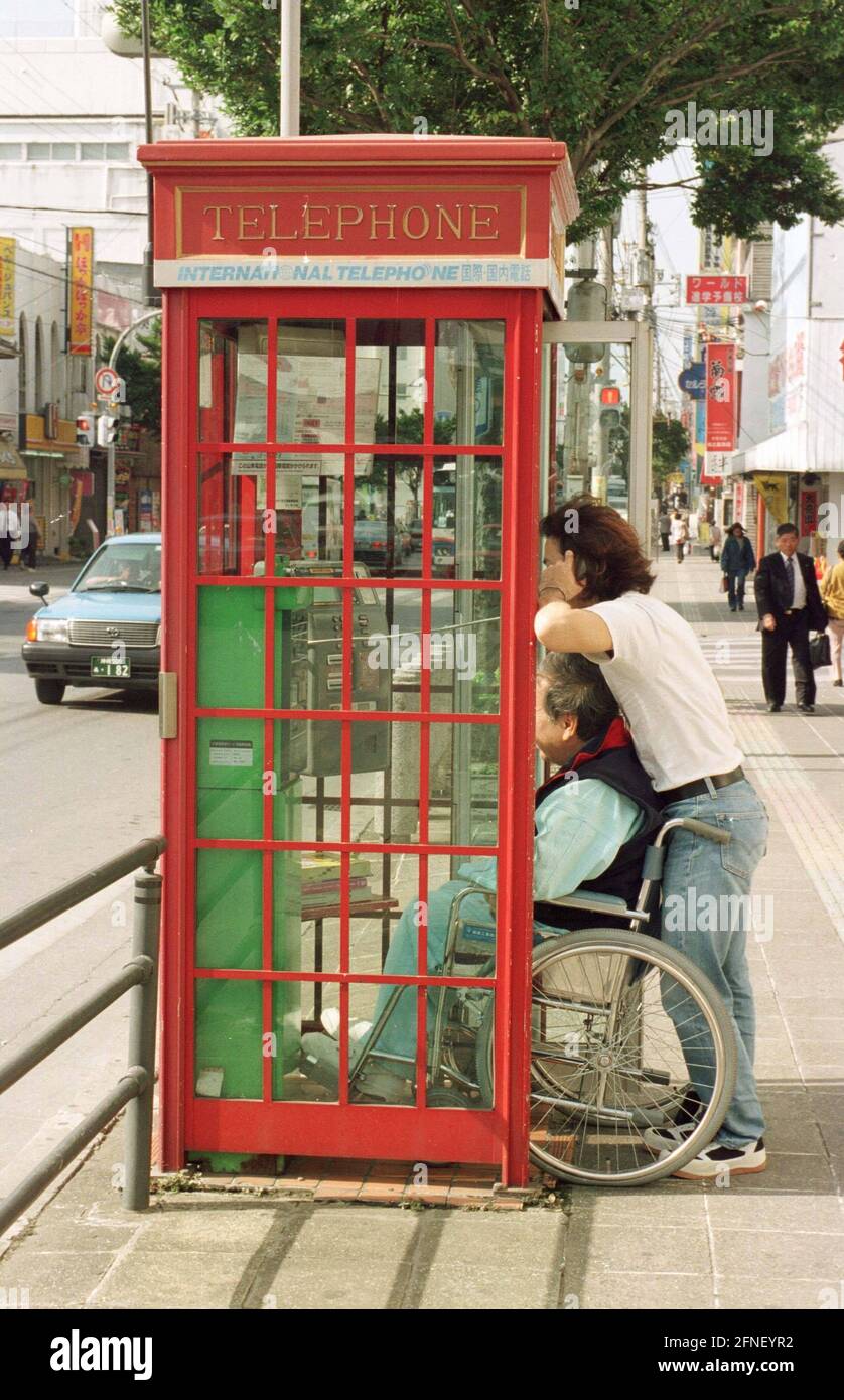 Wheelchair user making a phone call in a phone booth on Okinawa