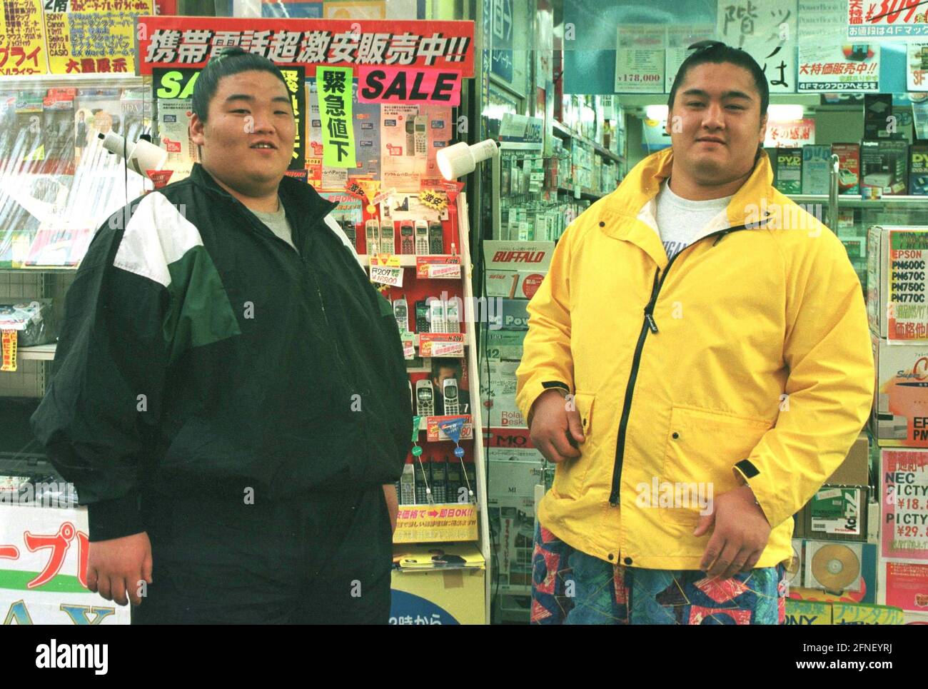 Tokyo's Akihabara district ('Eletric City') is the mecca of electronics in the Japanese capital. Two sumo wrestlers in front of a shelf with mobile phones on special offer. [automated translation] Stock Photo