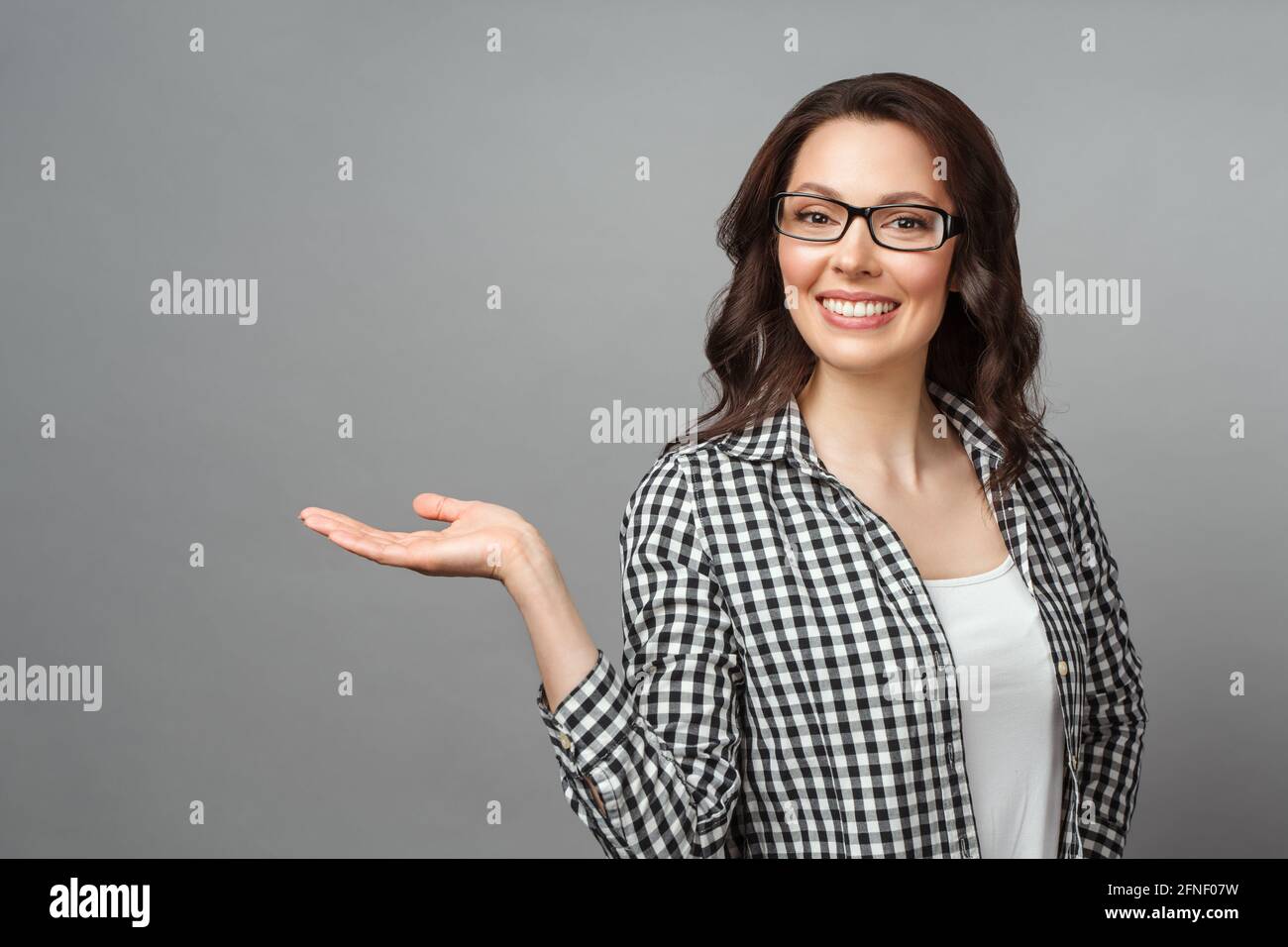 Young woman smiling and gesturing to copy space. Stock Photo