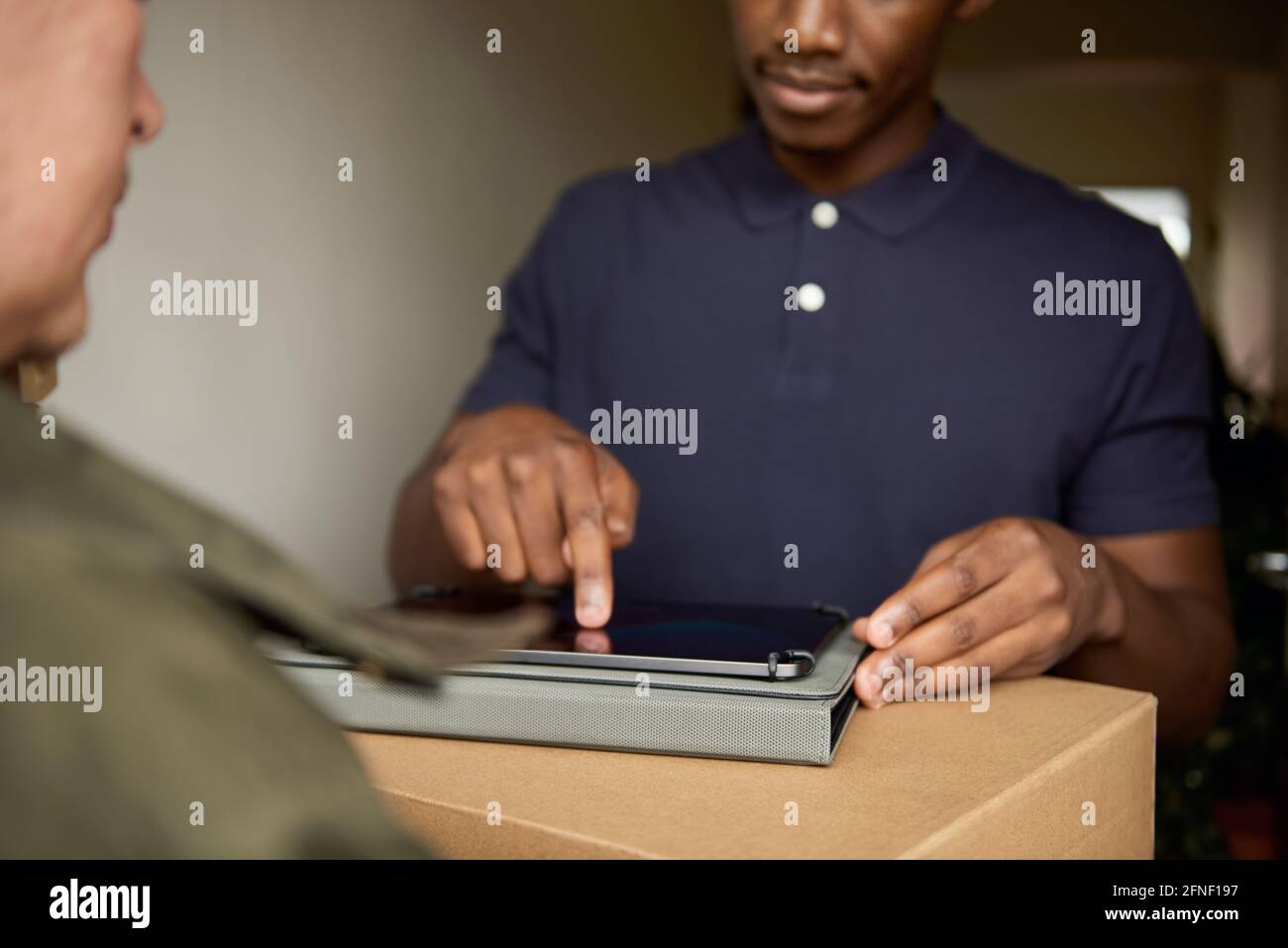 African man signing a digital tablet for a courier delivery Stock Photo