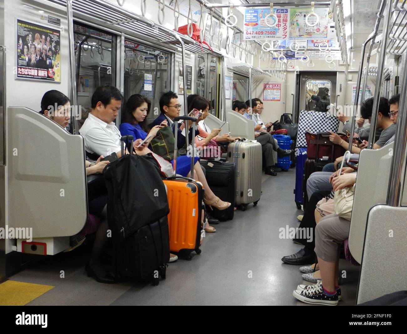 Japanese men and woman standing and sitting in the metro in Tokyo, Japan Stock Photo