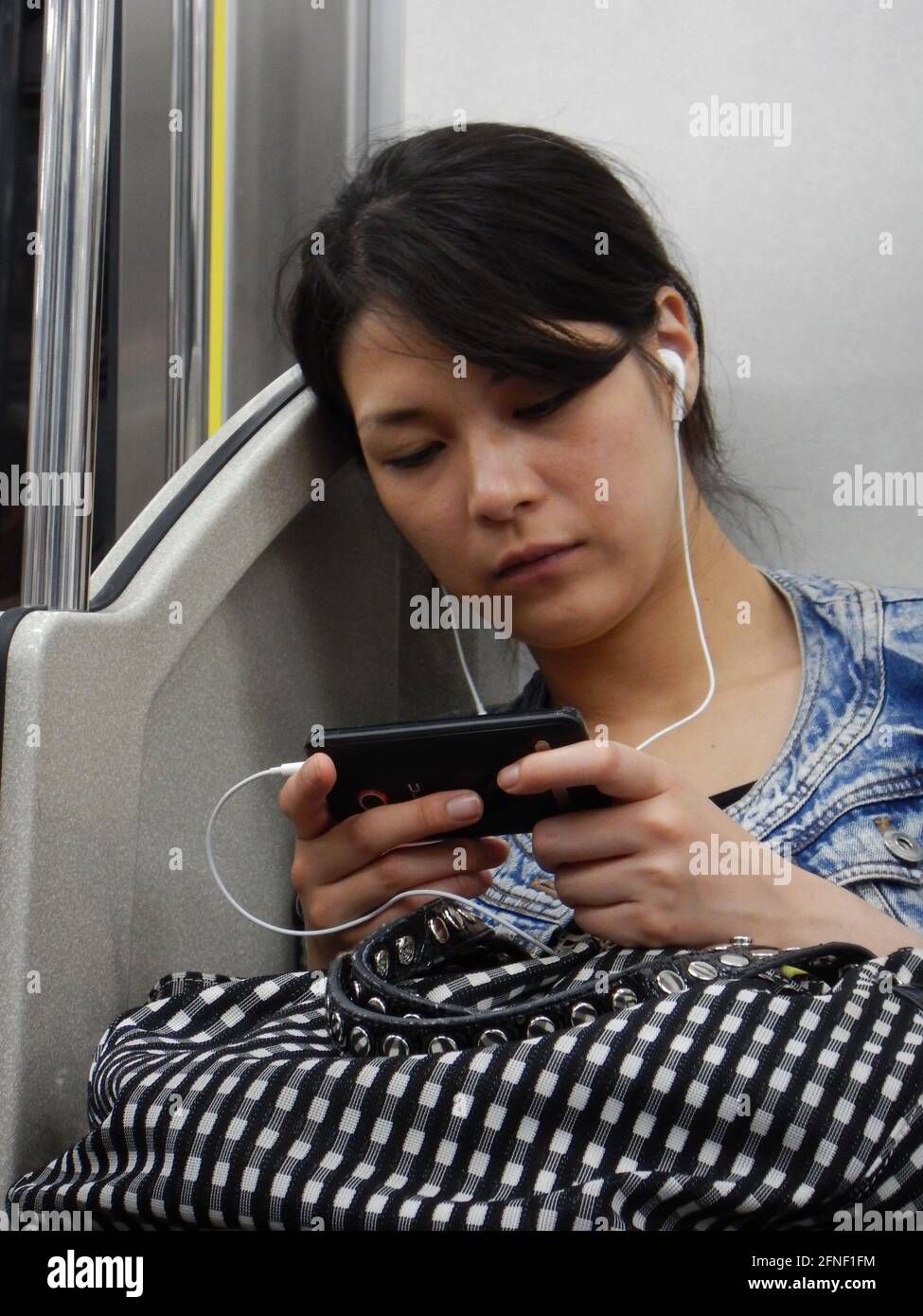 Japanese girl using their phone in the Metro, in Tokyo, Japan Stock Photo