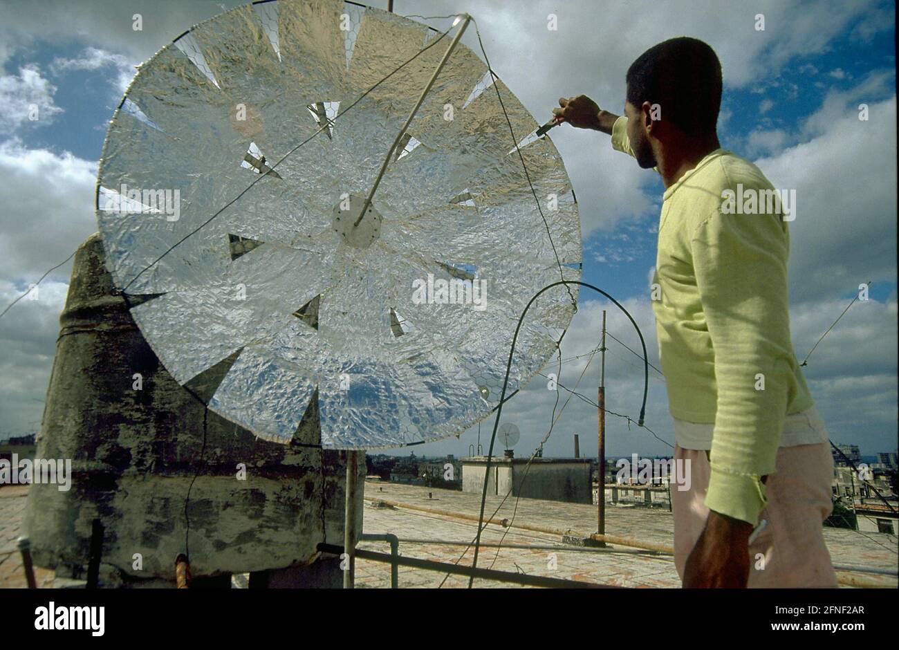 A Cuban man at a simply designed satellite dish installed on the roof of a house. [automated translation] Stock Photo