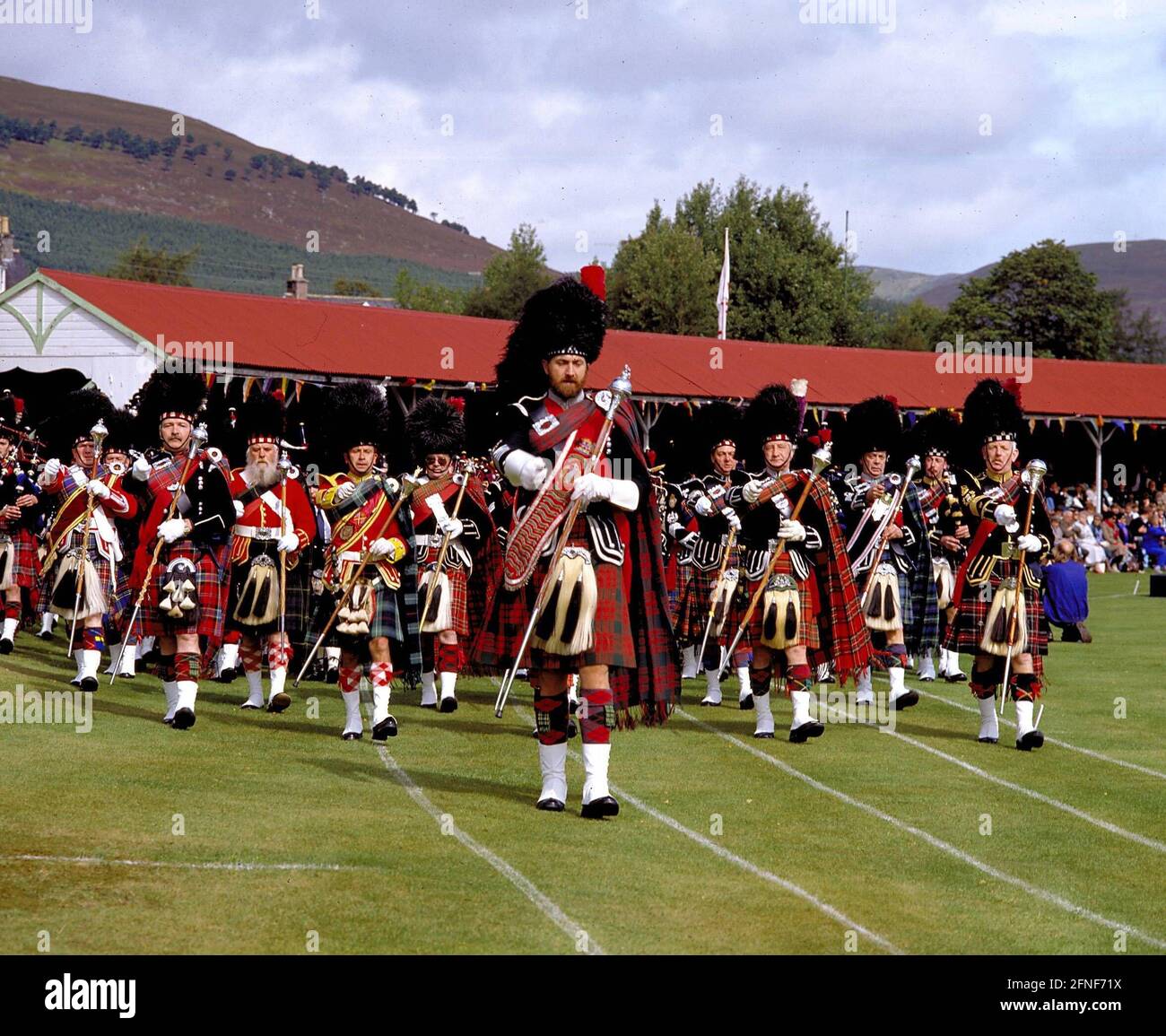 Parade of bagpipe bands at the Braemar Highland Games in front of the