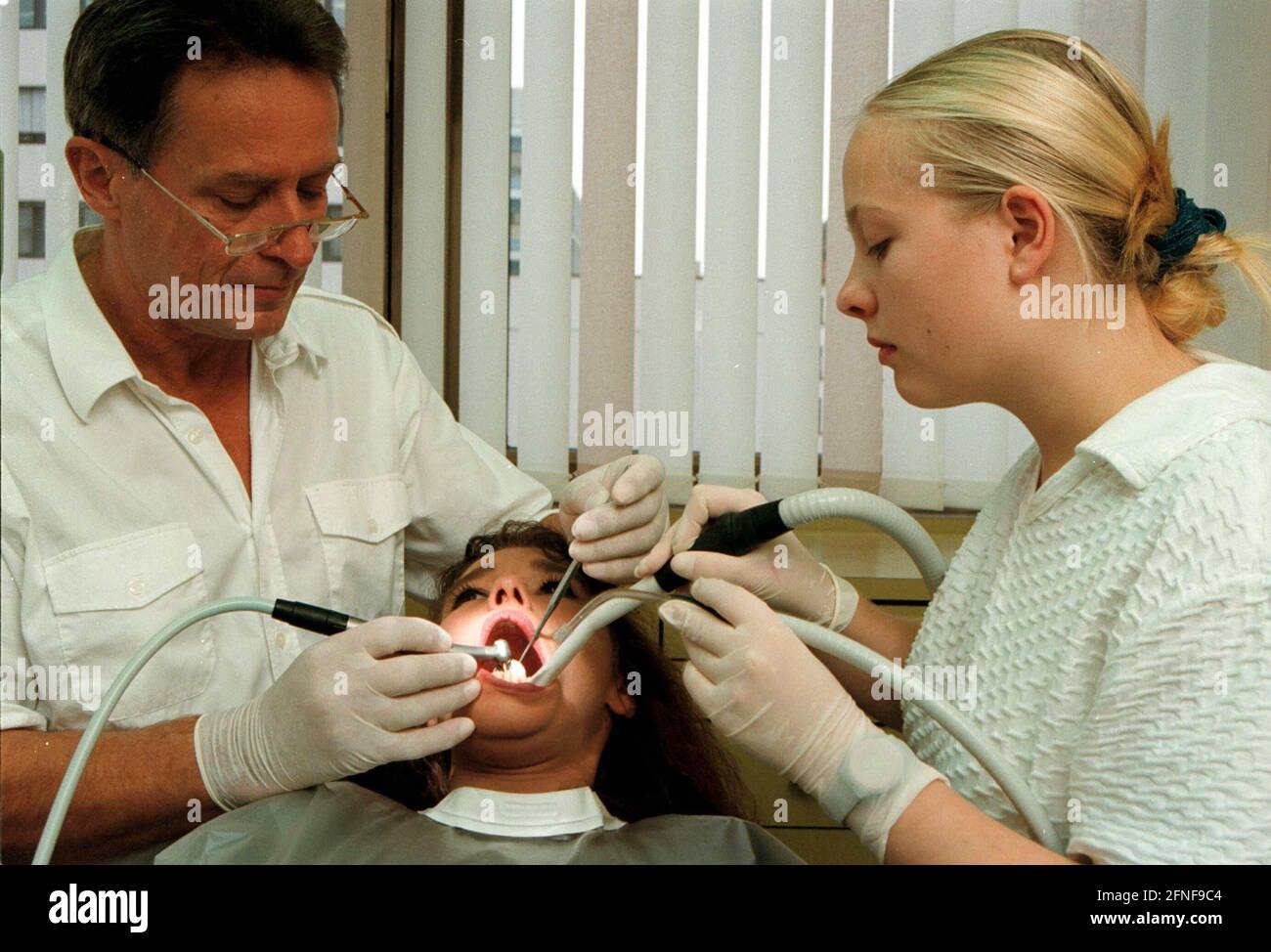 Dental treatment: Dentist and receptionist bend over the patient to be treated. [automated translation] Stock Photo