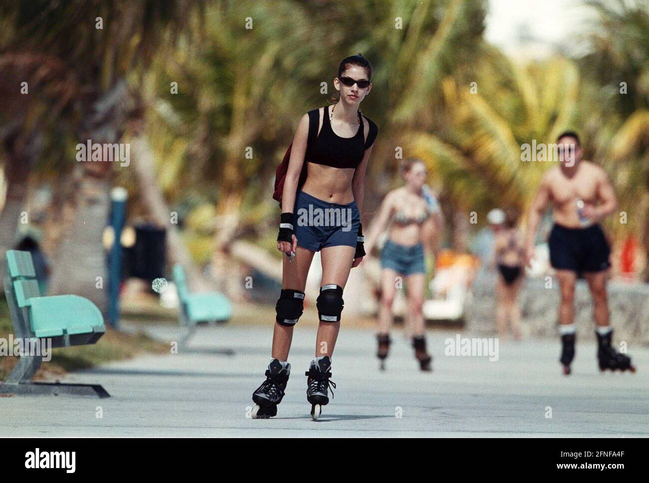 Roller-bladers ride on the boardwalk under palm trees in Miami Beach,  America. [automated translation] Stock Photo - Alamy